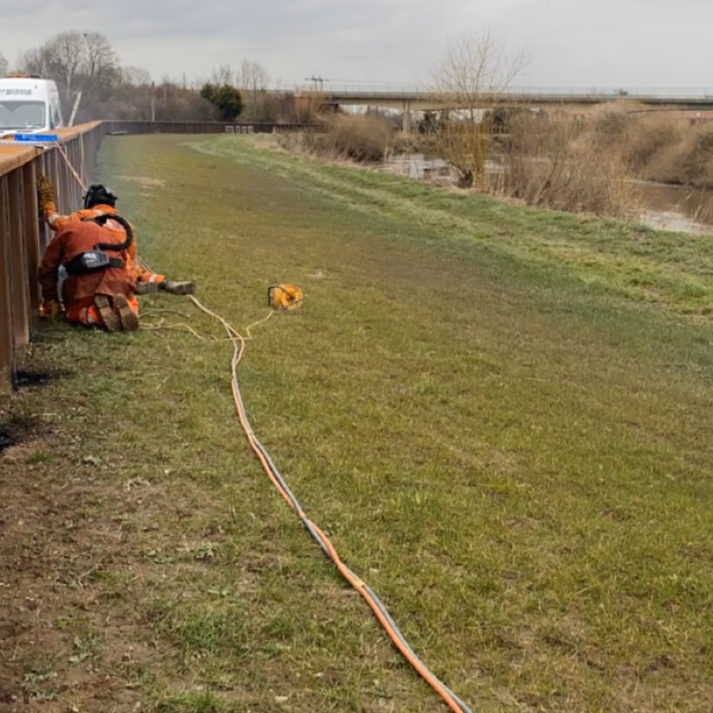 Site worker beside an installed steel sheet-pile wall.
